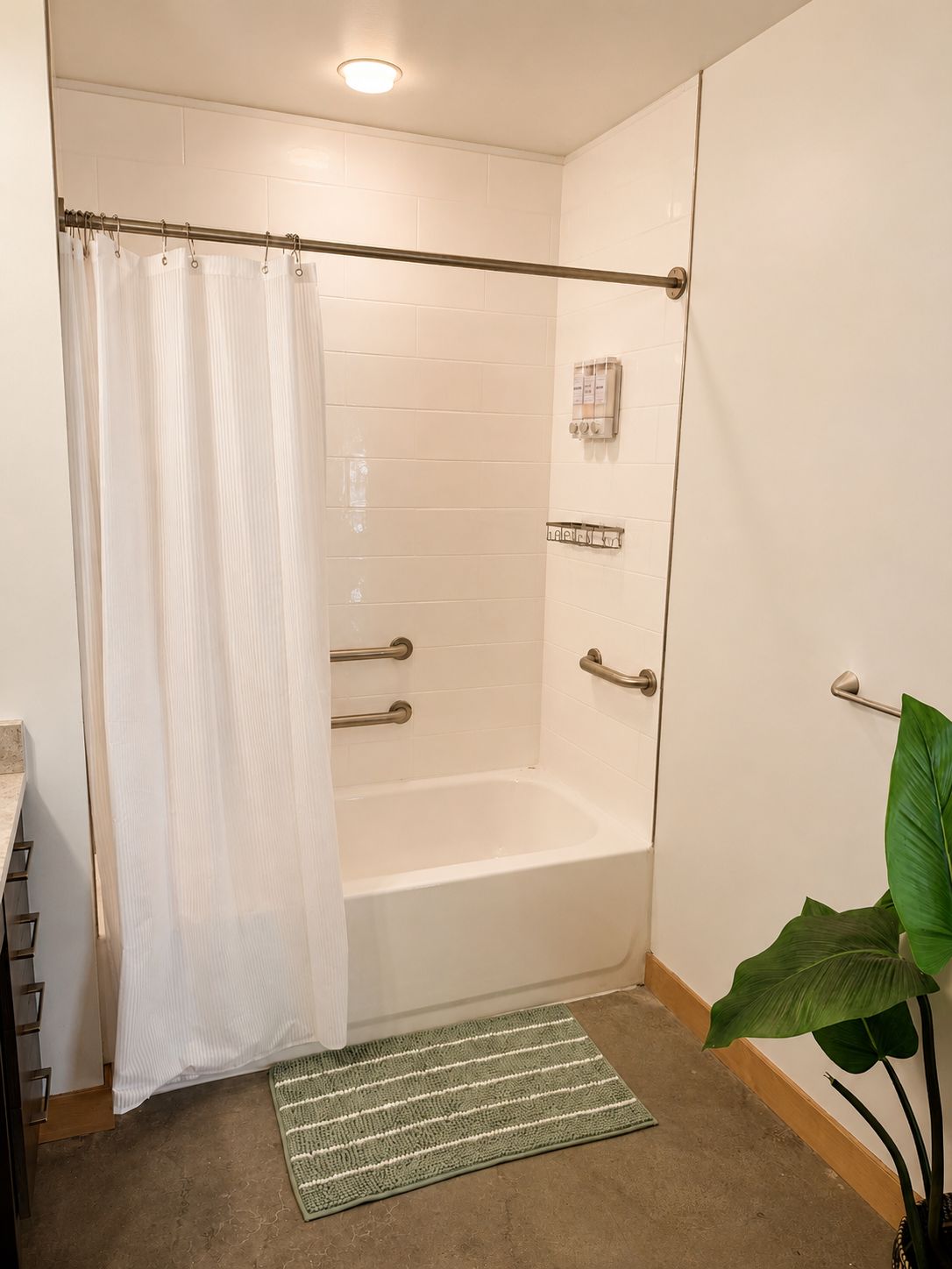 Eine begehbare Dusche mit Glastür, einem Handtuchhalter, einer Bedienkonsole und einem Topfpflanzen.