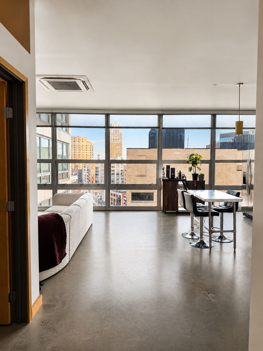 A modern apartment with a large window, a dining area, and a kitchen.