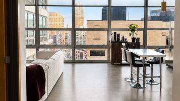 A modern apartment with a large window, a dining area, and a kitchen.