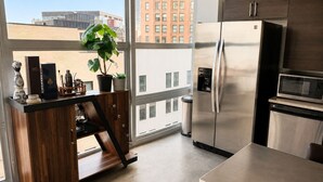 A modern kitchen with a stainless steel refrigerator, a microwave, and a wooden counter with a potted plant. - Modern Downtown Detroit Loft with Skyline views (Detroit)