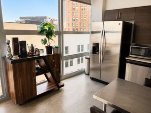 Eine moderne Küche mit einem Edelstahl-Kühlschrank, einer Mikrowelle und einer Holzausziehtheke mit einem Blumentopf.