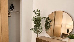 A bedroom with a wooden wardrobe, a round mirror, a potted plant, and a bedside table. - Modern Downtown Detroit Loft with Skyline views (Detroit)