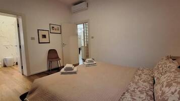Una camera da letto con un letto, una sedia e un'anta che dà su un bagno.