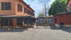 Un patio con zona de estar cubierta, un edificio de fachada roja y una puerta de acceso al estacionamiento.