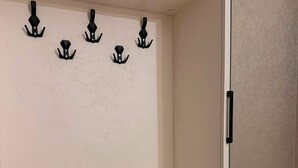 A storage area with a shelf holding folded towels and a wall-mounted towel rack. - Horizont Boutique Hotel (Telavi)