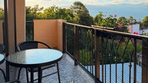 A balcony with a table and chairs, a view of trees and buildings, and a clear sky. - Horizont Boutique Hotel (Telavi)