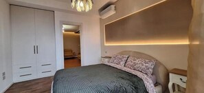 Un dormitorio con cama, armario, mesita de noche y lámpara de pared.