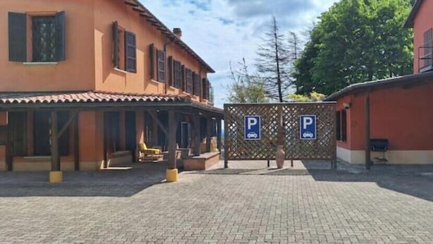 Ein Innenhof mit überdachter Sitzgelegenheit, ein Gebäude mit roter Fassade und einem Einfahrtstor.