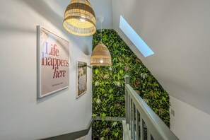 En trappa med en grön vägg och en inramad skylt med texten ”Här händer livet”.