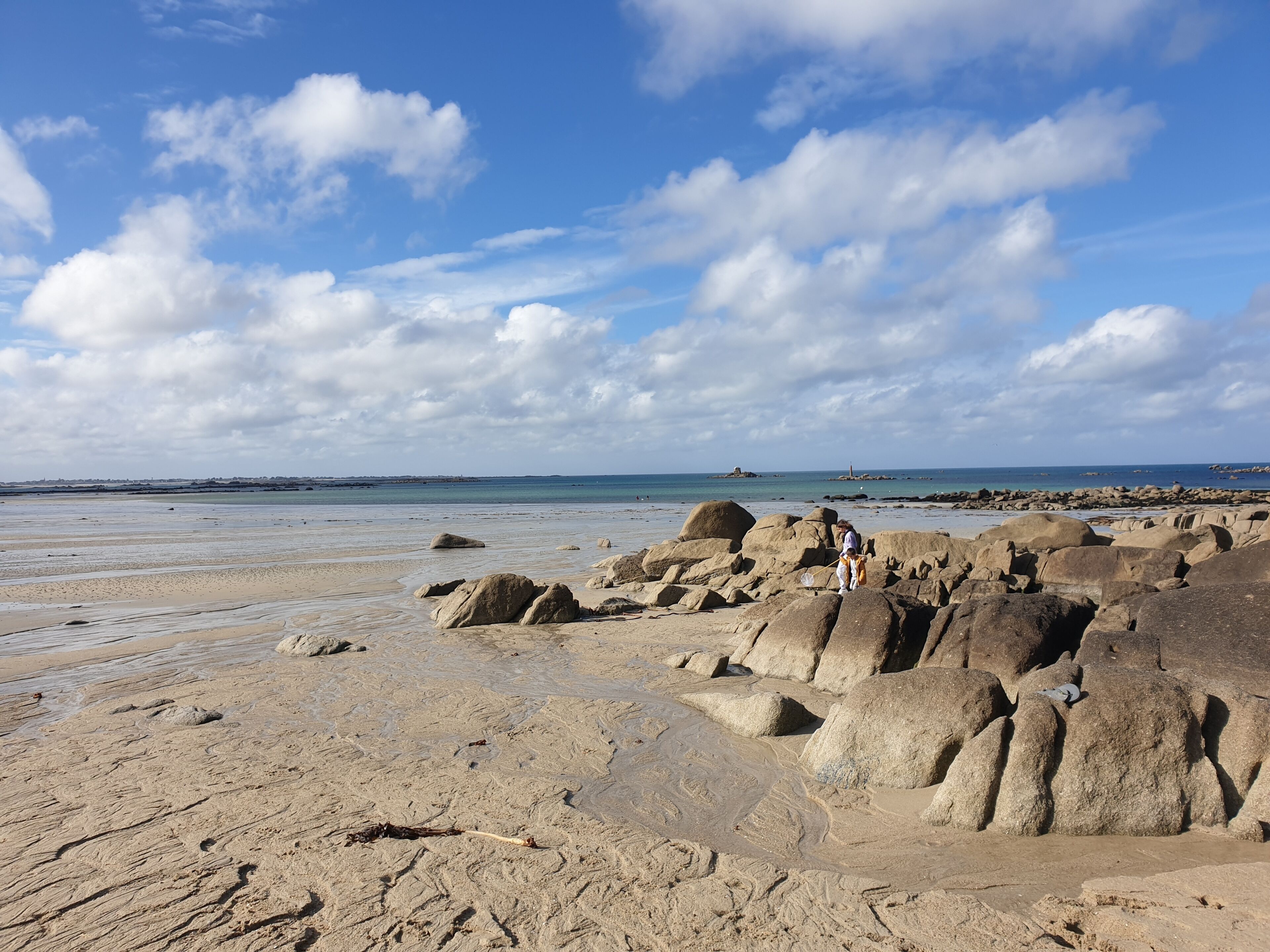 A rocky beach with large boulders and a clear sky.