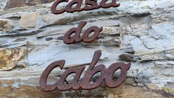 Een rustieke stenen muur met een metalen bord waarop 'casa do Cabo' staat.