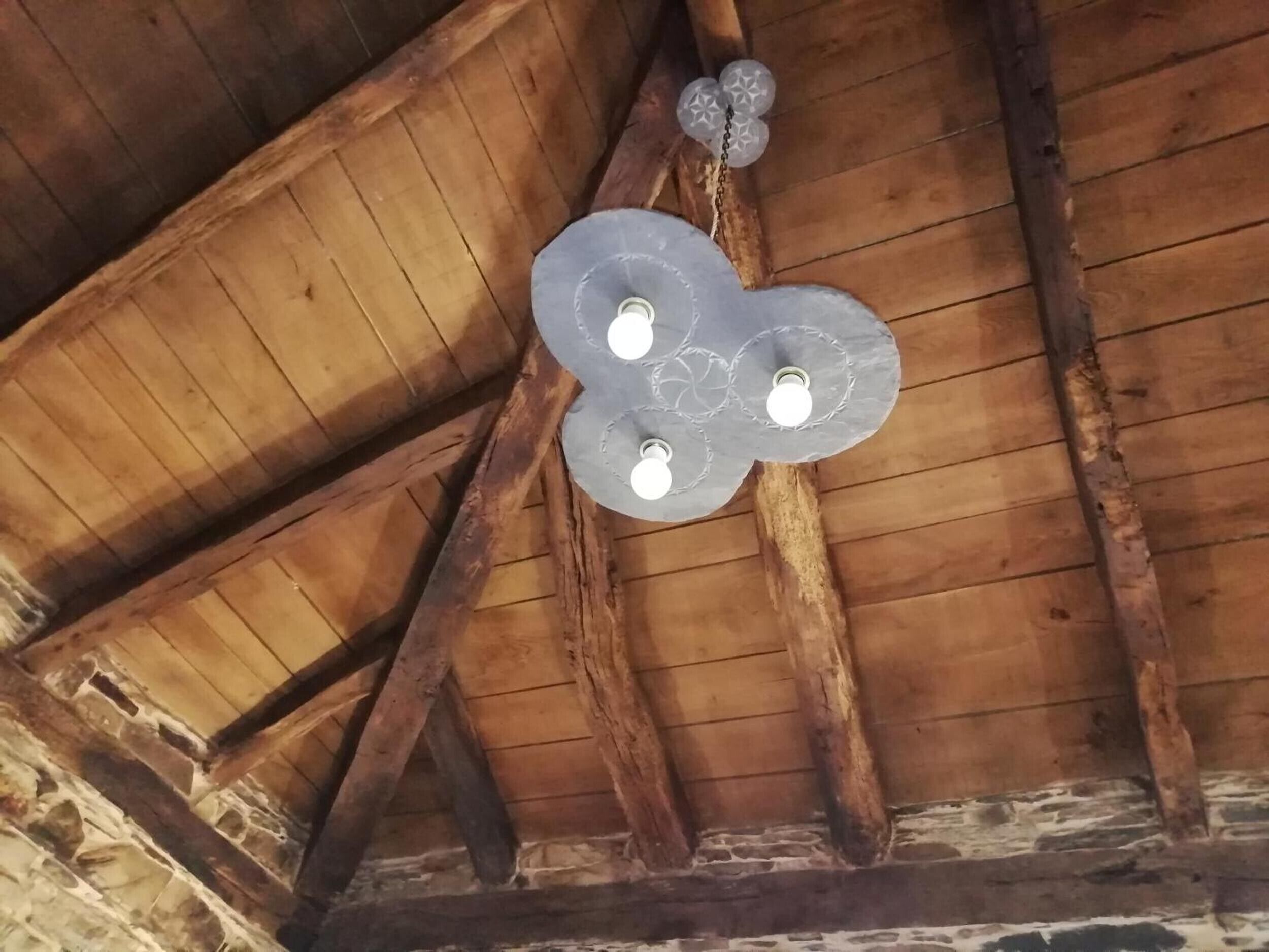 Eine Holzbalkendecke mit freiliegenden Holzbalken und einer dekorativen Leuchte.