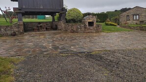 Un patio de piedra con una estructura de madera rústica y un edificio de piedra al fondo.