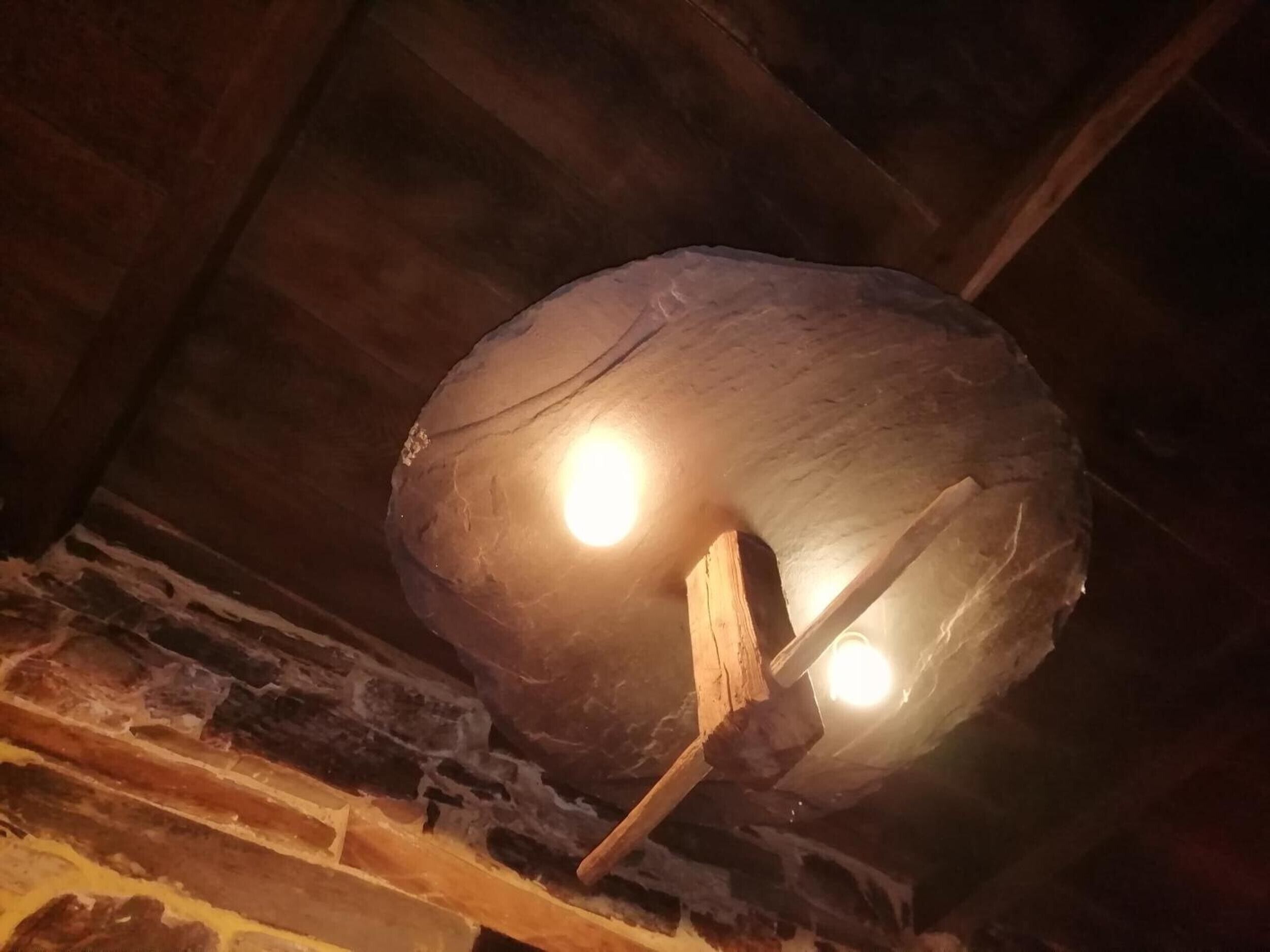 A rustic ceiling with exposed wooden beams and a rough, textured stone-like structure.
