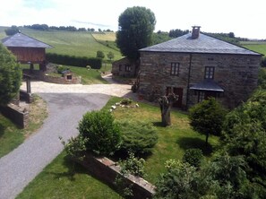 A stone building with a paved driveway and a small structure to the left.