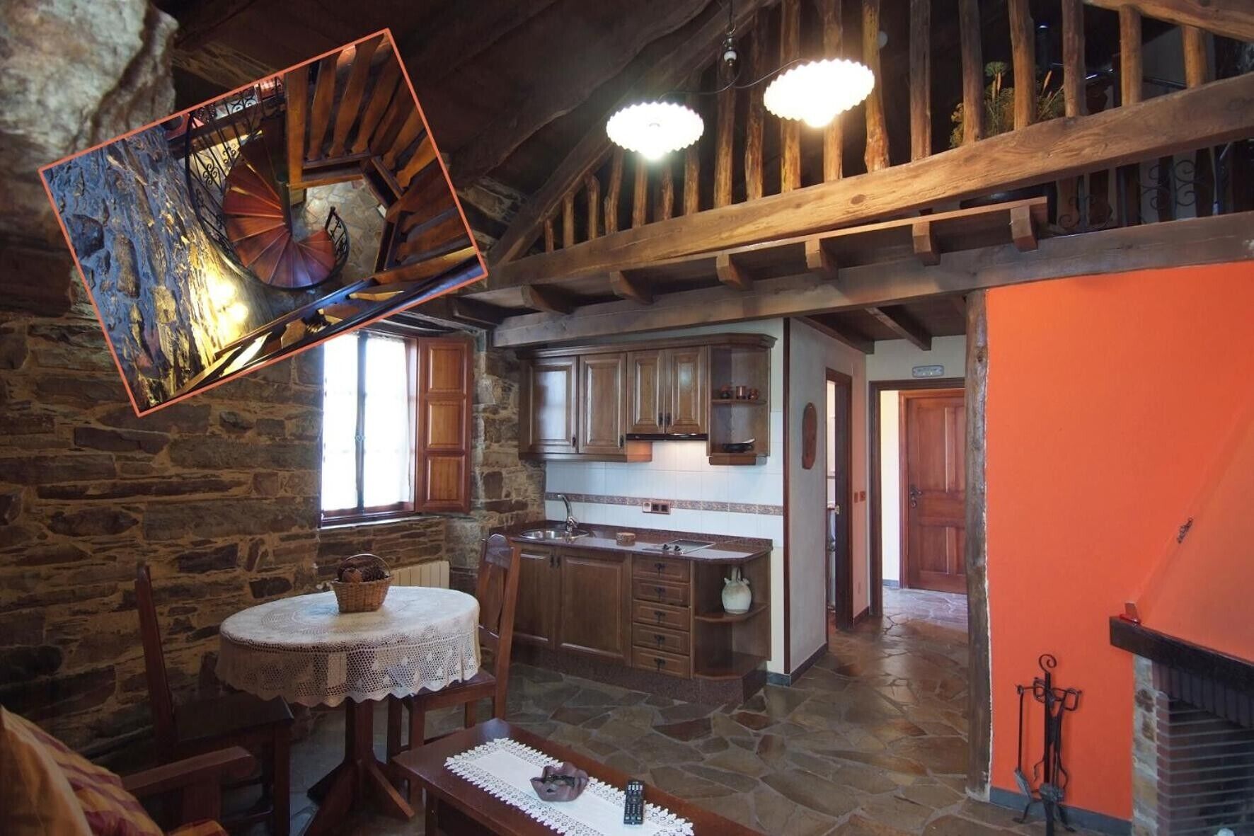 Ein rustikaler Innenraum mit Steinwand, einer Holztreppe und einer Küchenzeile mit Holzschränken und einer gefliesten Spritzschutzwand.