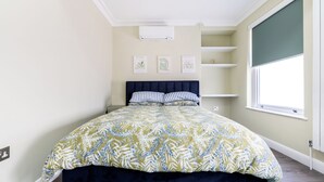 Ein Schlafzimmer mit einem Bett, einem Fenster und Wandbildern.