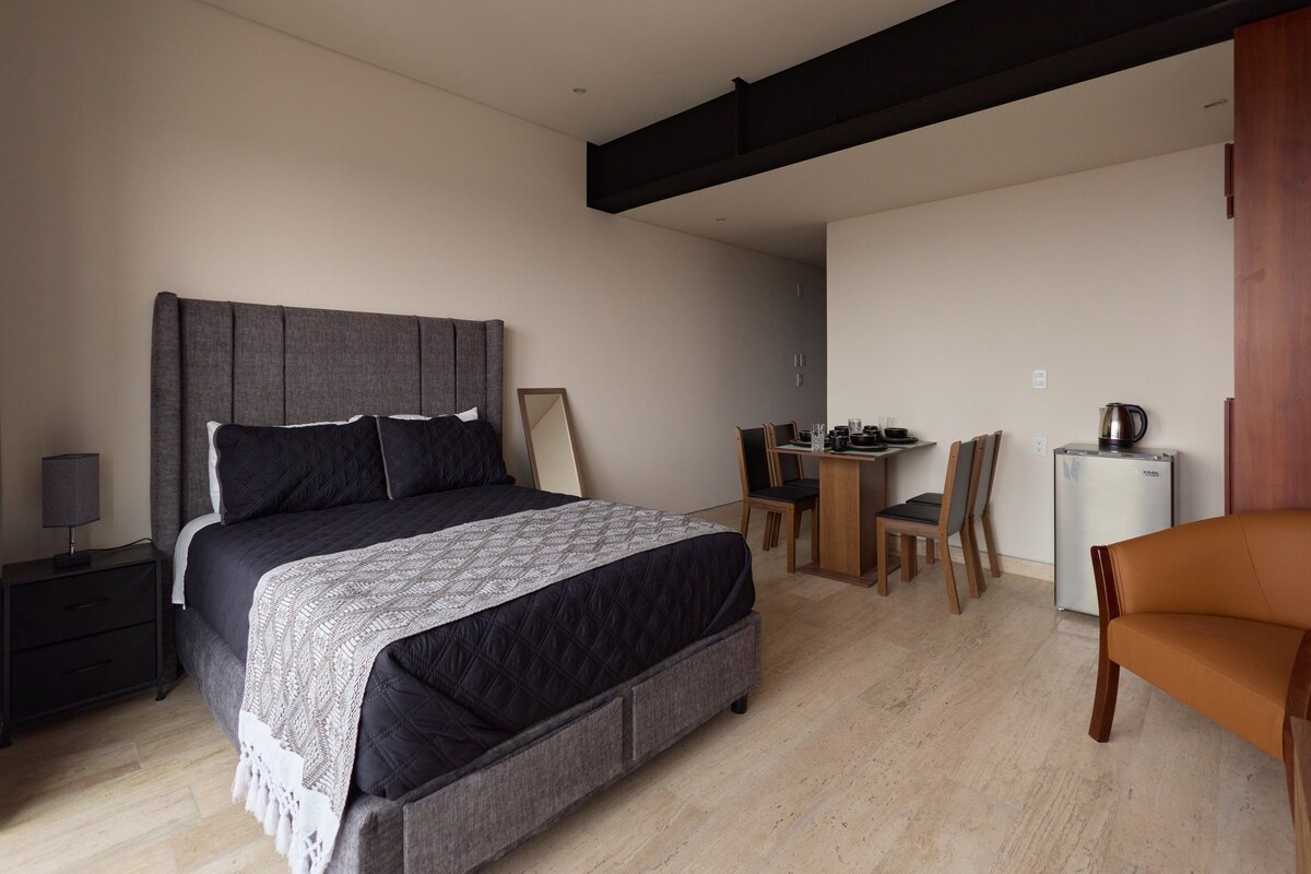 Une chambre à coucher comprenant un lit, une table de chevet, une lampe et un bureau avec des chaises.