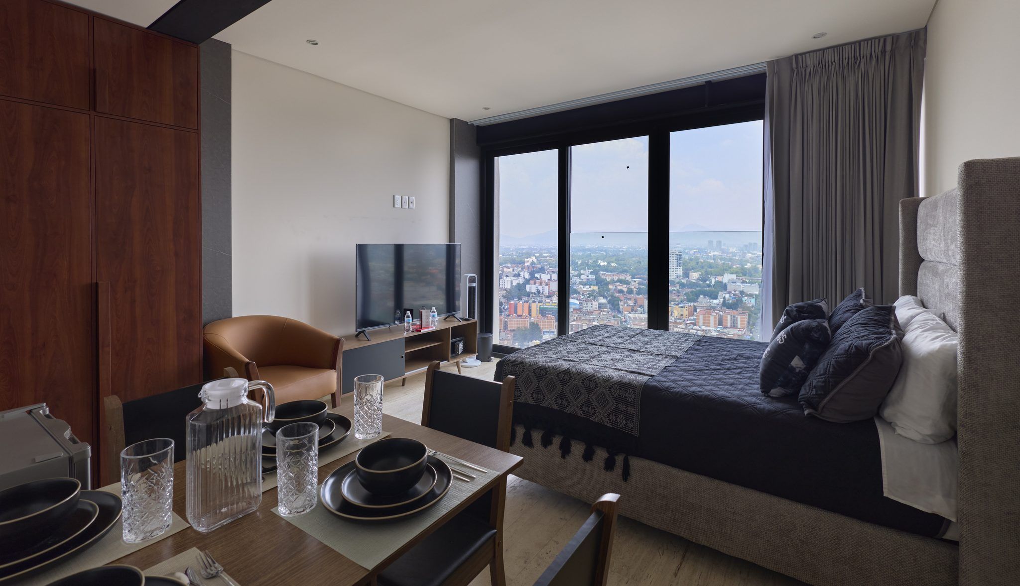 Ein modernes Hotelzimmer mit einem großen Bett, einer Sitzecke, einem Fernseher und einer Essecke für zwei Personen.