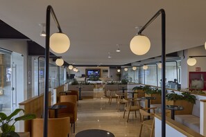 Ein modernes Interieur mit Sitzbereichen, einer Rezeption und einem Fernsehbildschirm.