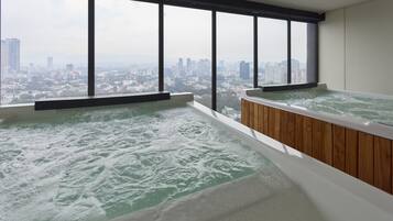 A room with two hot tubs and a city view.