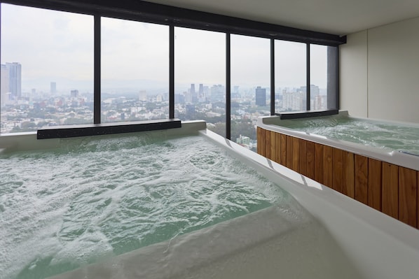 Quarto com duas banheiras de hidromassagem e vista para a cidade.