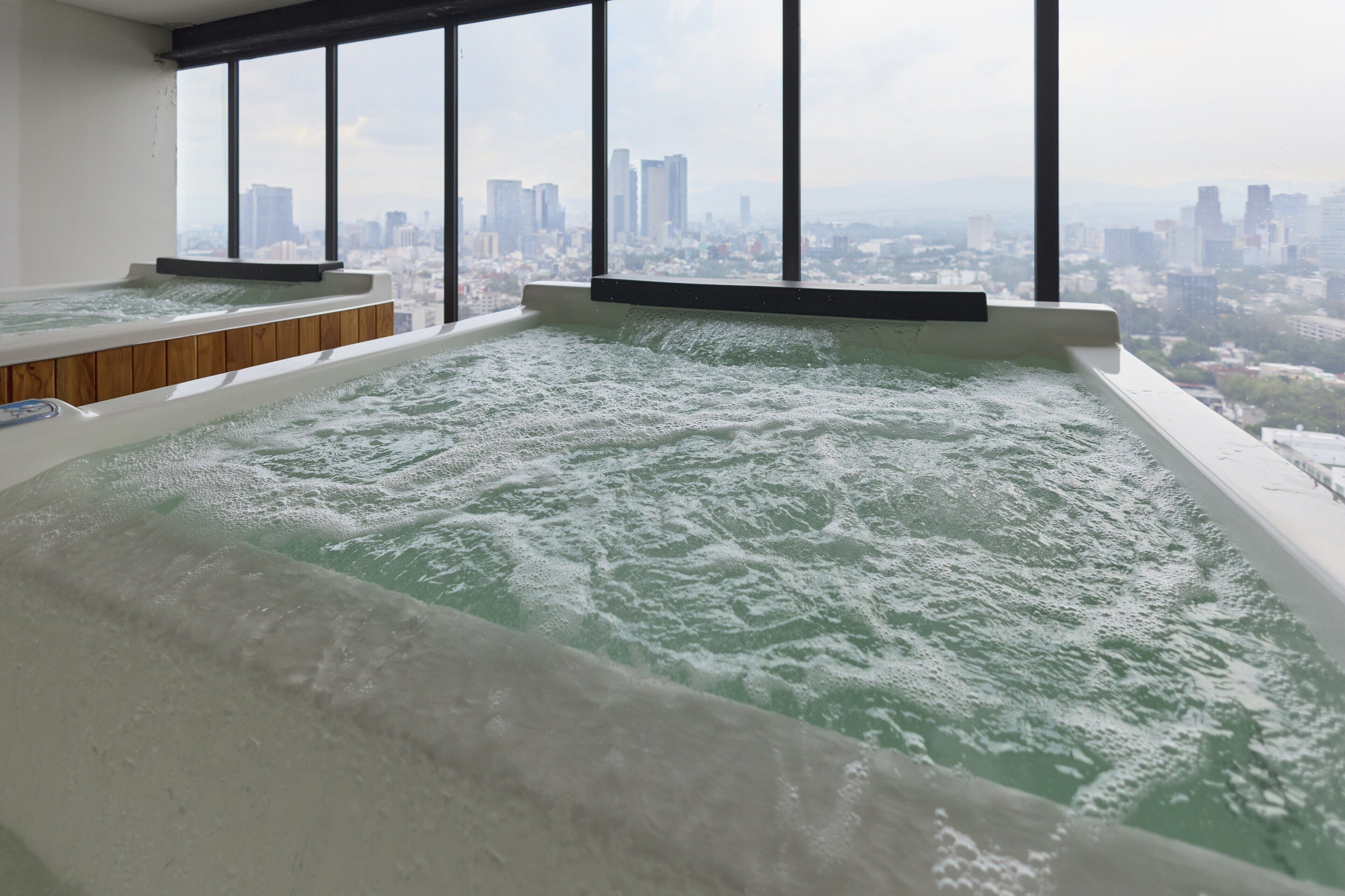 A hot tub with a cityscape view through large windows.