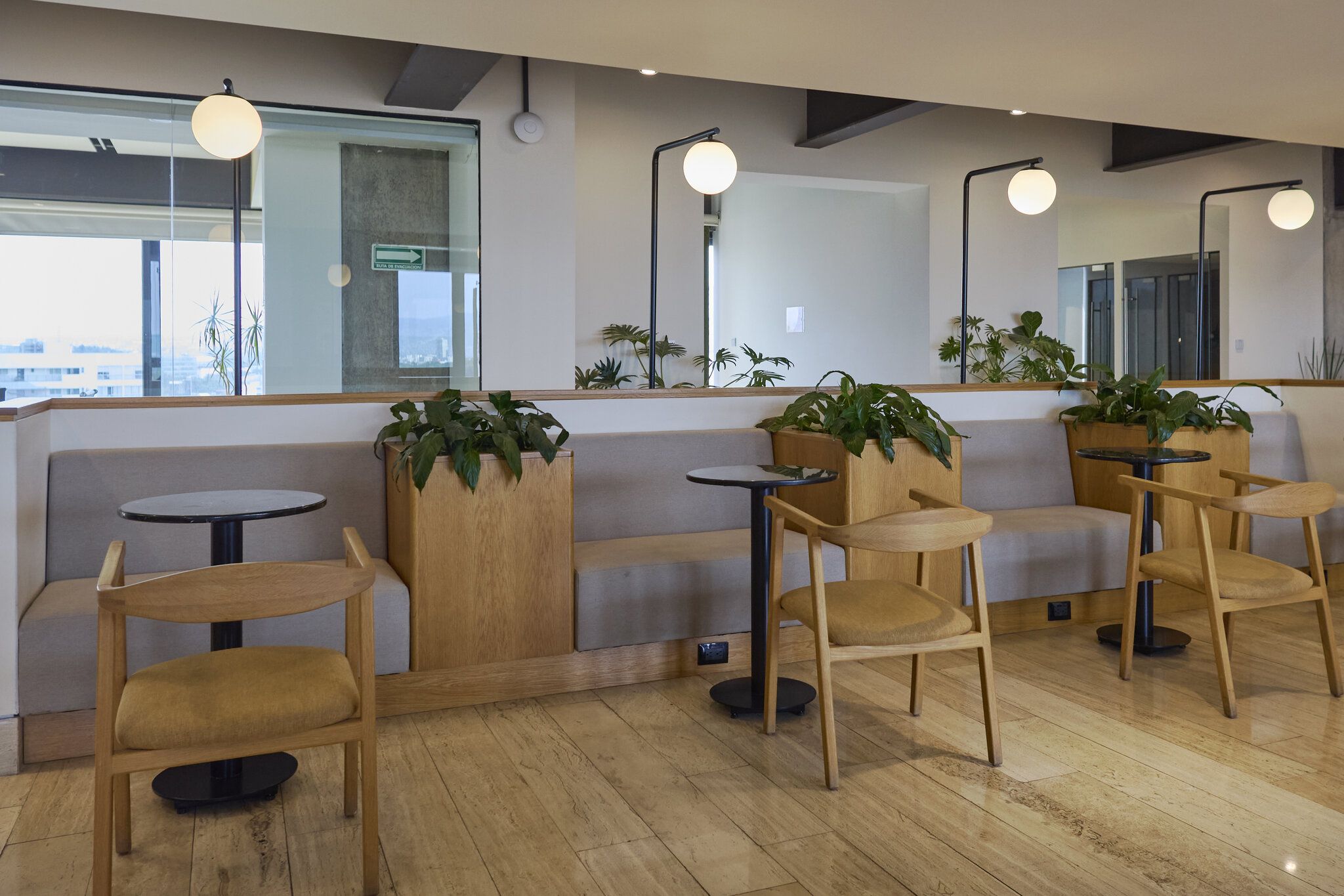 A modern interior with seating arrangements, including sofas and tables, and potted plants.