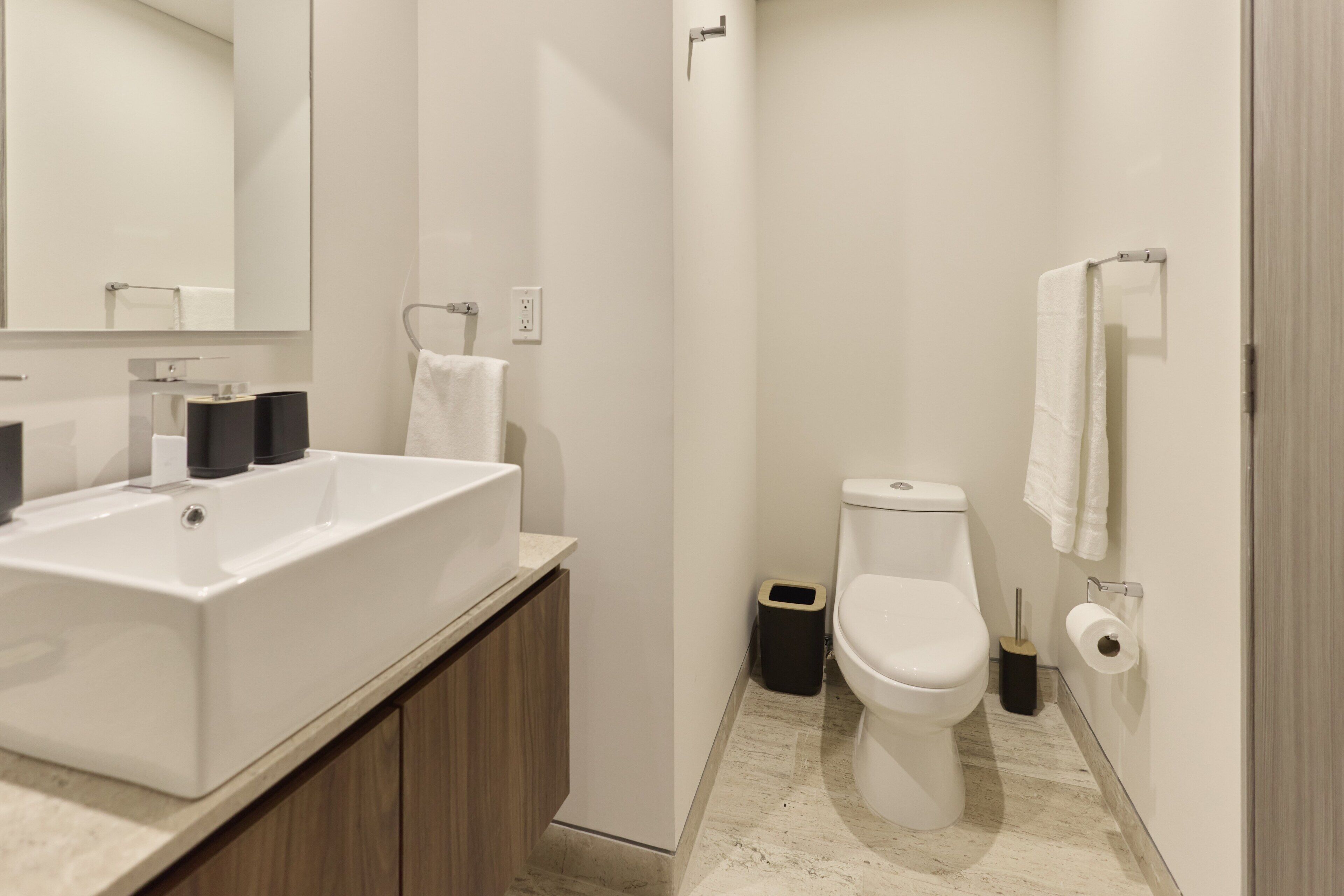 A modern bathroom with a large white sink, a toilet, and a shower area.