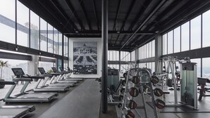 Un gimnasio con cintas de correr, máquinas de pesas y mancuernas.
