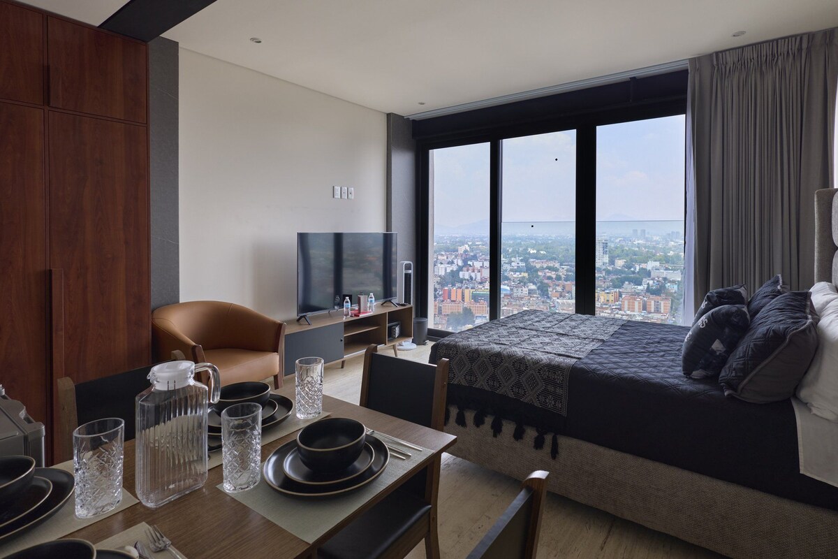 Une chambre d’hôtel moderne dotée d’un grand lit, d’une télévision, d’un coin repas et offrant une vue sur le paysage urbain.