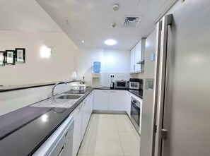 Eine moderne Küche mit weißen Schränken, einem Edelstahl-Kühlschrank, einer Mikrowelle und einem Wasserspender.