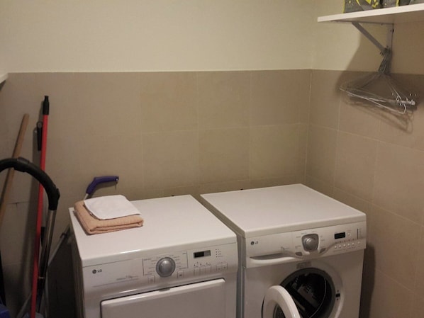 A laundry area with two white washing machines and a drying rack.
