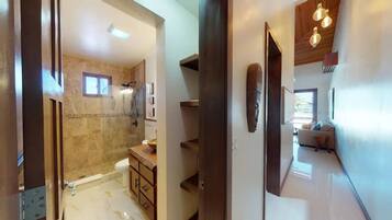 A modern bathroom with a glass-enclosed shower, a wooden vanity, and a marble floor.