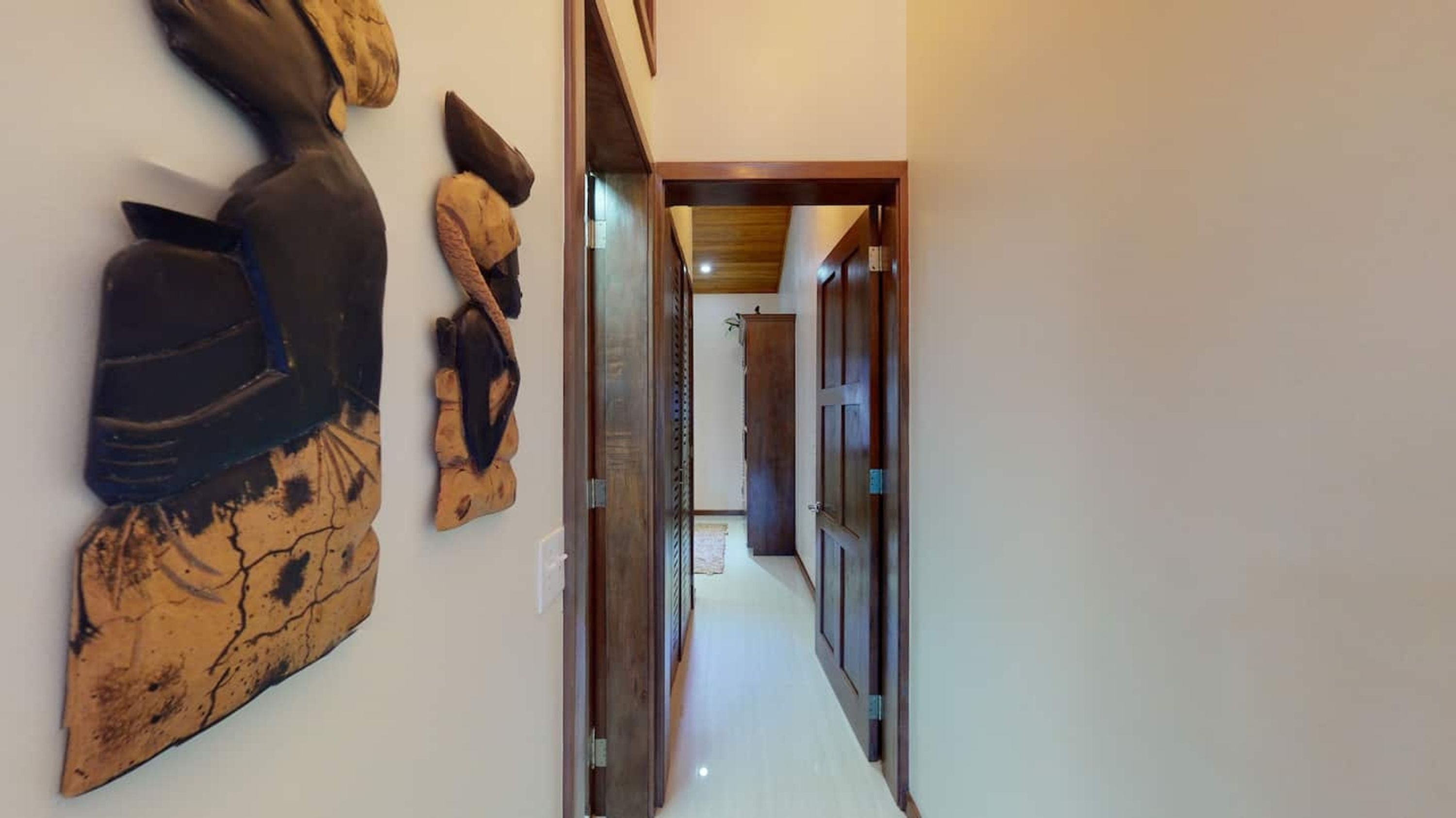 A hallway with a wooden door frame and a wall-mounted sculpture.