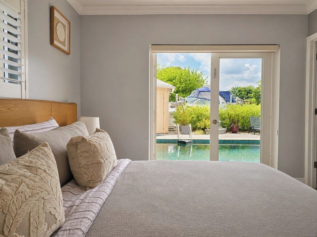 Un dormitorio con una cama grande, vistas a una piscina y una puerta que da al exterior.