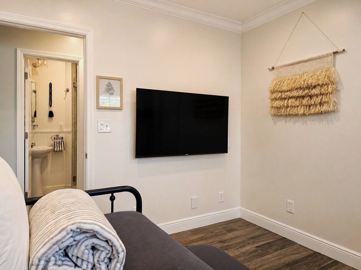 Une chambre d’hôtel avec un lit, un téléviseur à écran plat fixé au mur, un porte-serviettes et un petit tableau encadré.