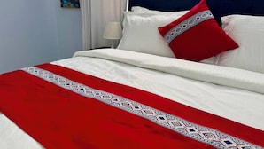 A neatly made bed with a red and white patterned bedspread, white pillows, and a dark headboard. - Moonlight Hotel (Dar es Salaam)