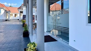 A hotel entrance with a glass facade, columns, and a tiled pathway. - Moonlight Hotel (Dar es Salaam)