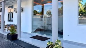 A hotel entrance with a glass door, columns, and outdoor seating. - Moonlight Hotel (Dar es Salaam)