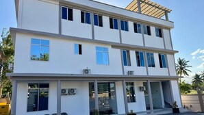 A modern two-story building with a flat roof, large windows, and a covered entrance area. - Moonlight Hotel (Dar es Salaam)