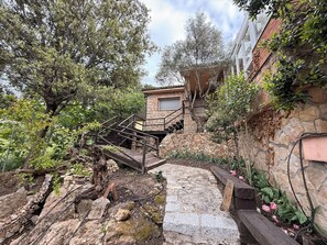 A stone staircase leading to a building with a stone facade, surrounded by greenery and trees.