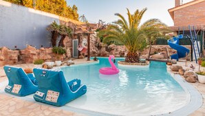 Ein Schwimmbecken mit Liegestühlen, einer Wasserrutsche und einem Flamingo-Schwimmding.