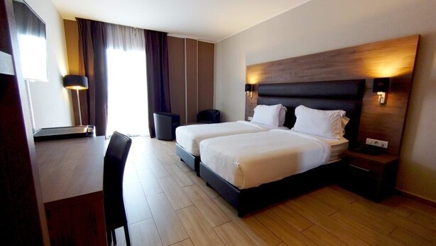 A hotel room with a double bed, bedside tables, a desk, and a chair. - Hotel Le Zenith Oran (Es Senia)