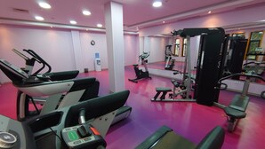 A gym with exercise equipment, a water dispenser, and a mirror. - Hotel Le Zenith Oran (Es Senia)