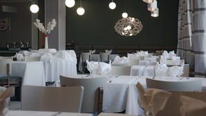 A restaurant with round tables covered in white tablecloths, each set with white napkins and cutlery. - Hotel Le Zenith Oran (Es Senia)