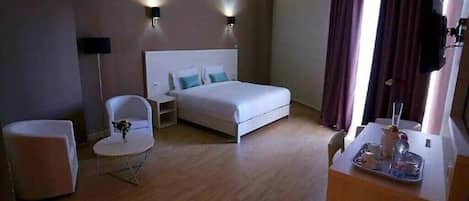Habitación de hotel con cama, una silla, una mesita con bandeja y un espejo.