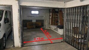 A garage with a car parked on the left, a window above a door, and a metal gate on the right.