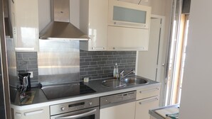 A modern kitchen with stainless steel appliances, a black tiled backsplash, and white cabinetry.