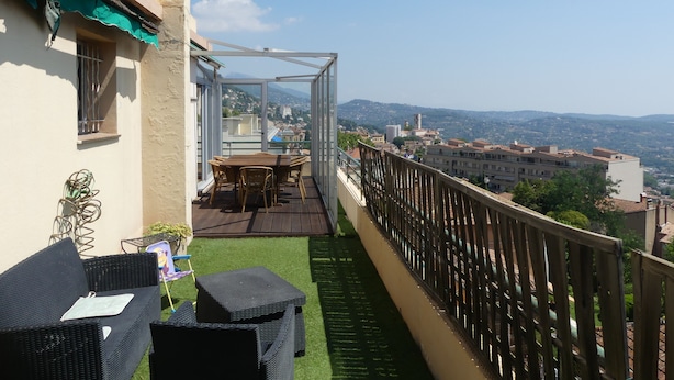 A balcony with a table and chairs, a view of the city, and a wooden railing.